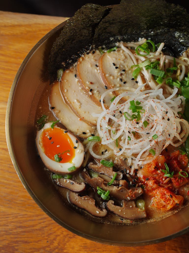 A flavorful ramen bowl with egg, mushrooms, and seaweed in a cozy setting.