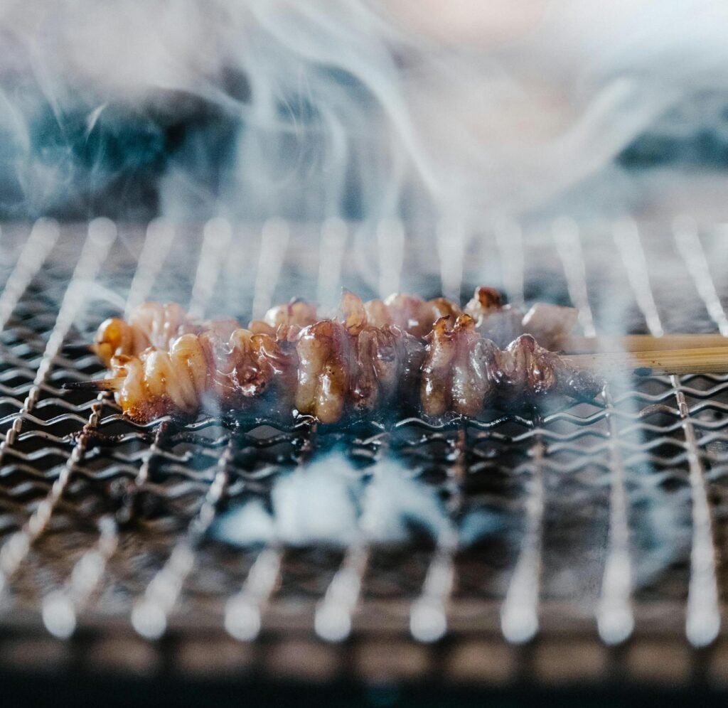 Close-up of a delicious grilled yakitori skewer cooking on a smoking grill.