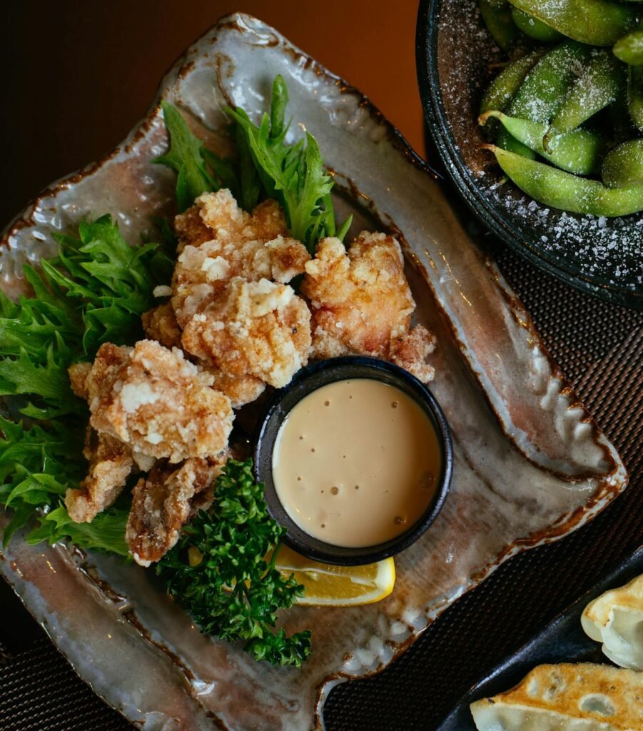 Delicious japanese street food of karaage, A table of asian dishes including dumplings, fried chicken, and edamame, perfect for a savory dining experience.