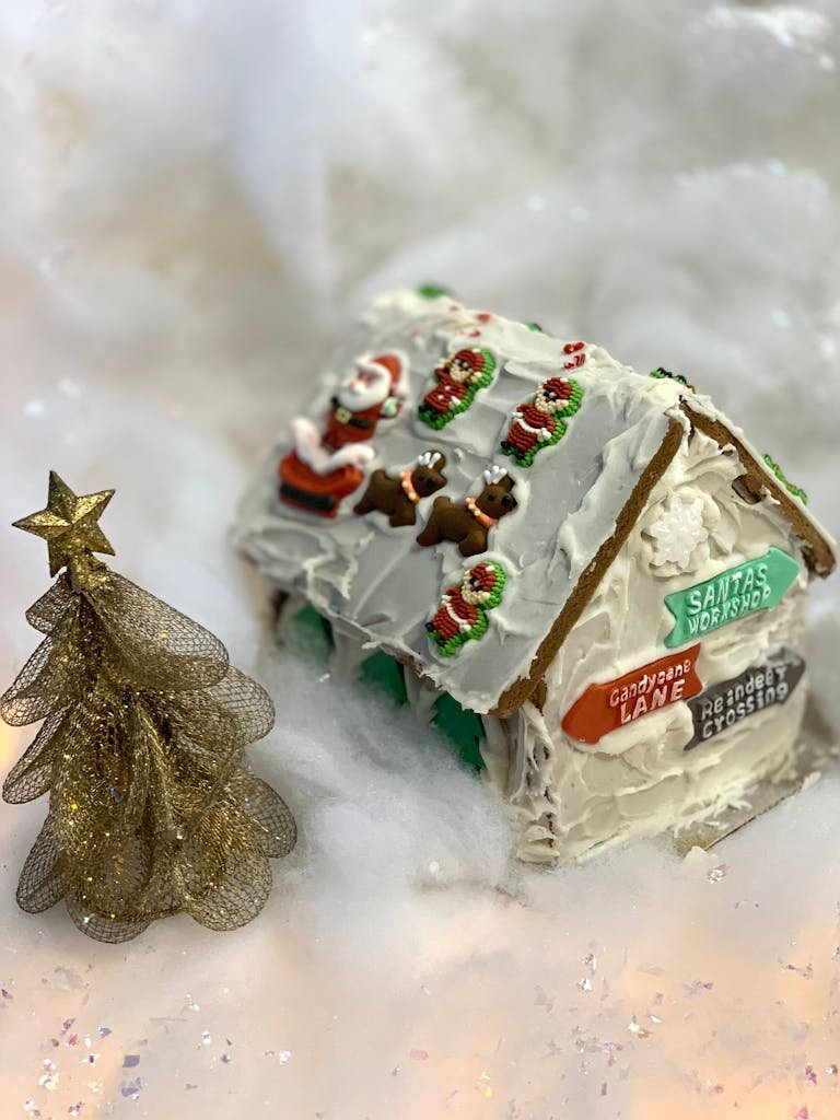 Detailed gingerbread house with festive decor and a glittery tree, perfect for holiday seasons.