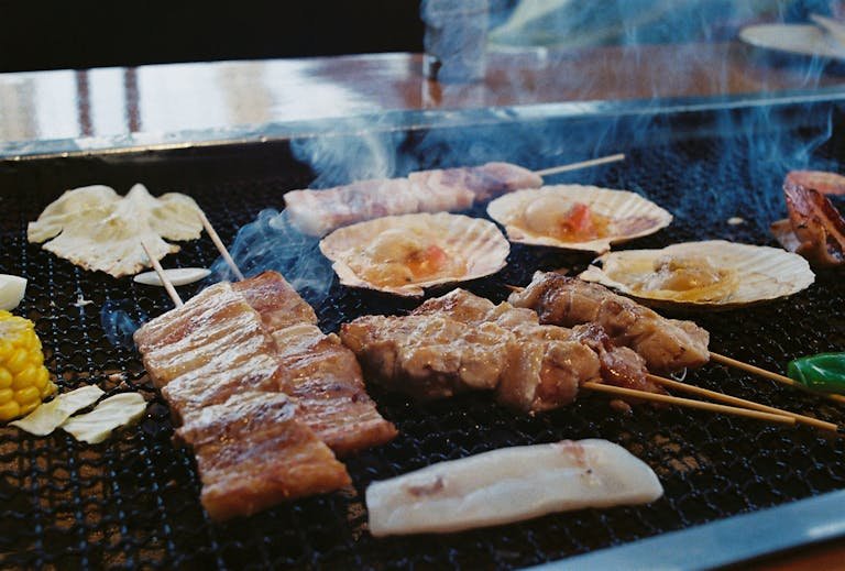 Grilled Japanese skewers and seafood sizzling on an open barbecue in Nagano, Japan.