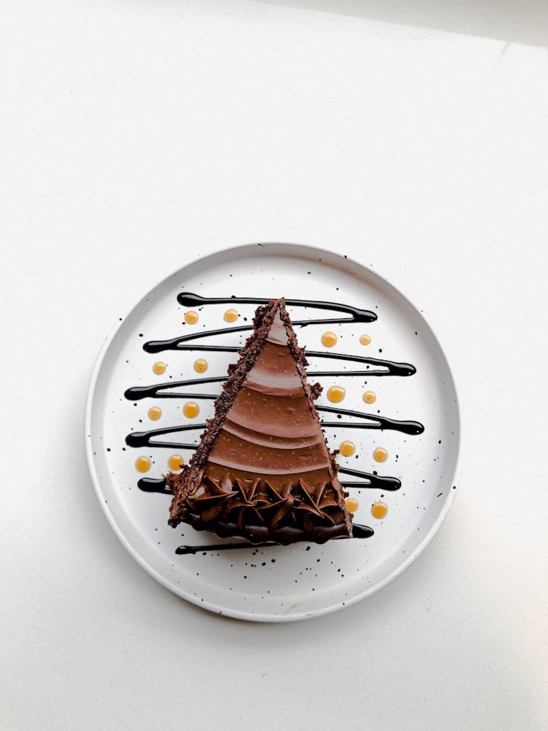 Indulge in a delicious slice of chocolate cake with artistic drizzle on a white plate.