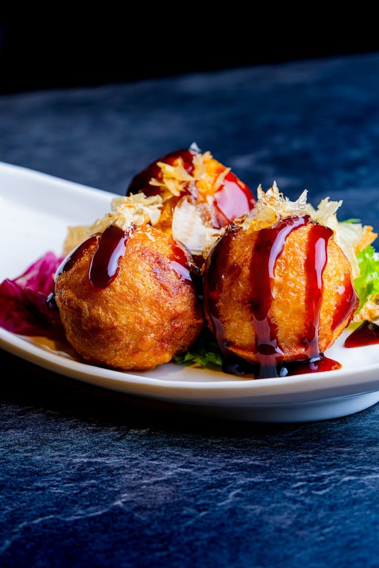 Mouthwatering takoyaki topped with sauce and garnish served on a stylish plate.