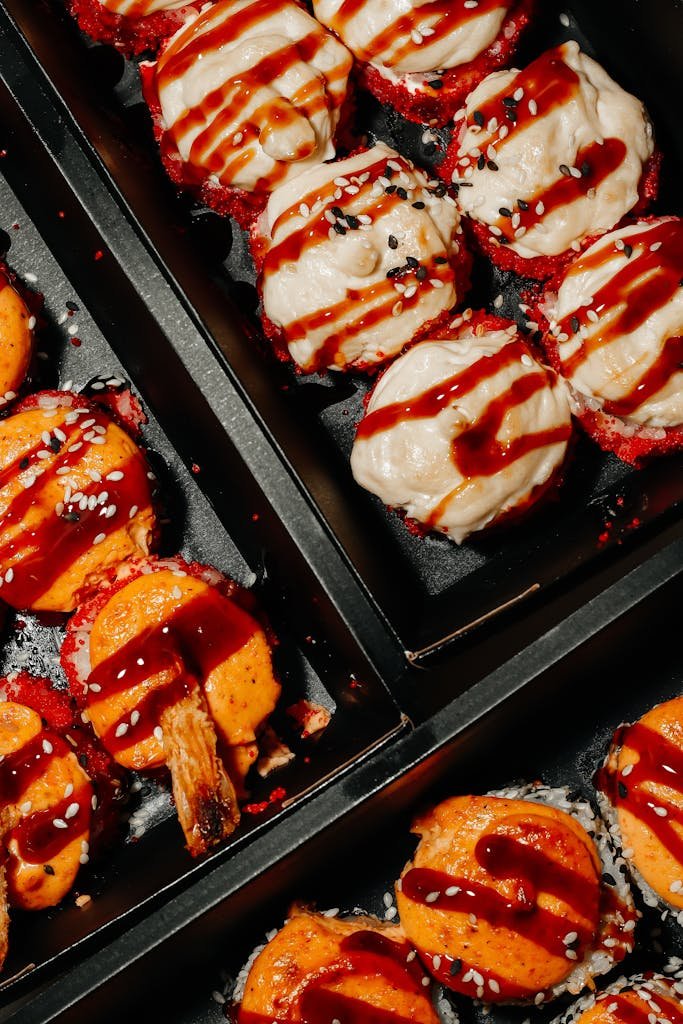 Top view of authentic Japanese street food of flavorful takoyaki drizzled with savory sauce in a black tray.