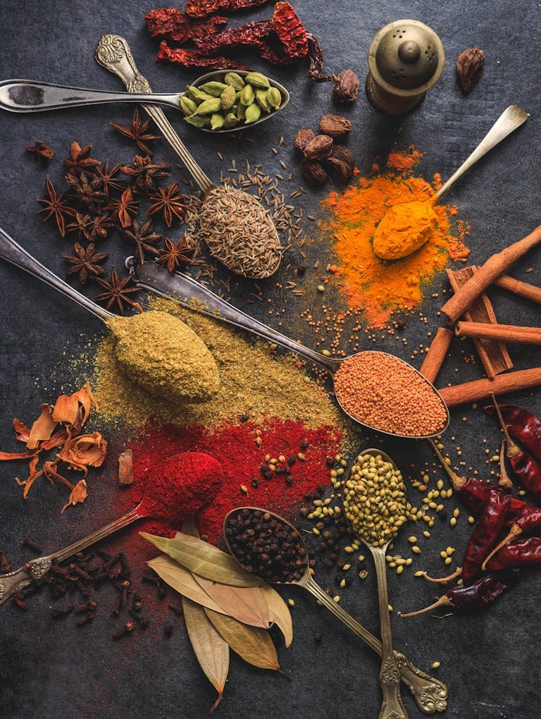 Vibrant array of exotic spice blends including turmeric, cumin, and chili arranged on a dark surface.