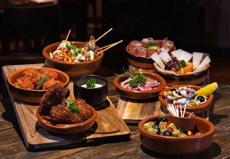 Spanish tapas dishes served in rustic style on a wooden table.
