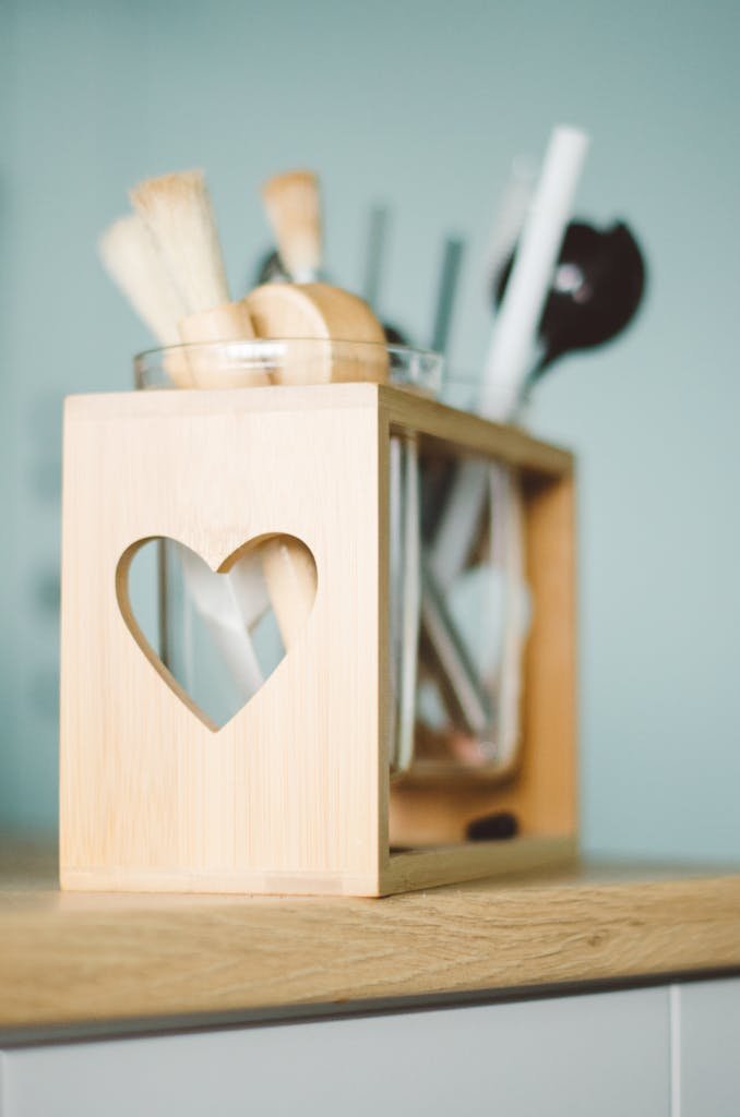 Close-up of sustainable kitchen tools of a wooden utensil holder with a heart cutout, perfect for kitchen decor.