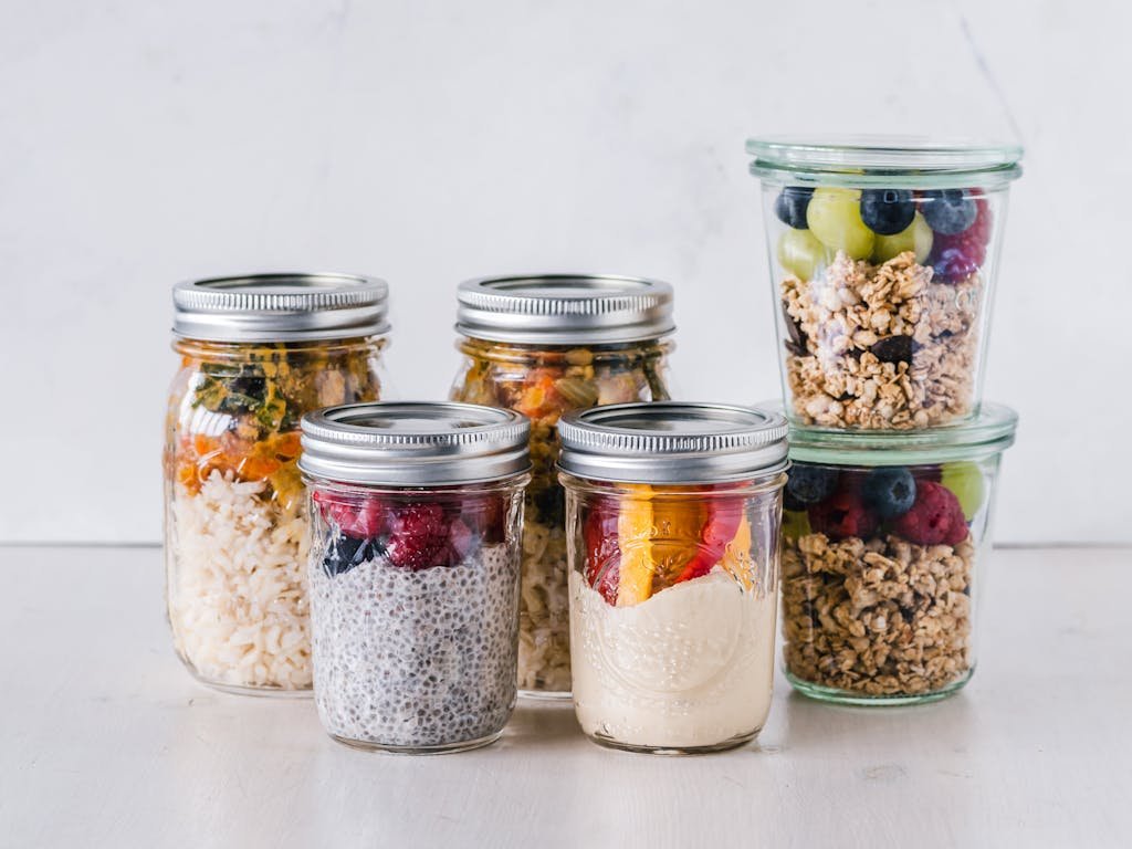 Close-up of healthy food in mason jars containing granola, fruits, and yogurt.