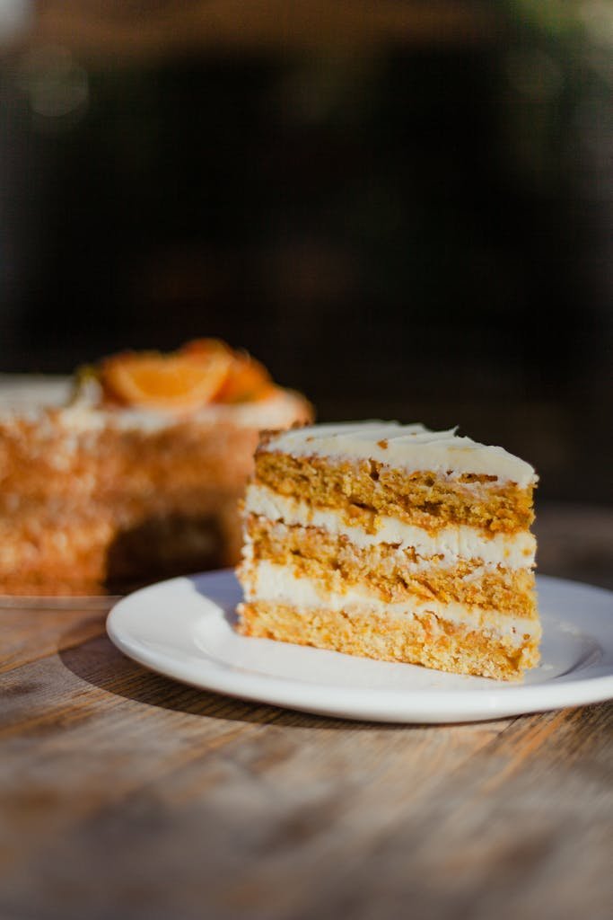 Homemade classic carrot cake recipe showing a close-up of a layered carrot cake slice with cream cheese frosting on a plate, perfect for dessert lovers.