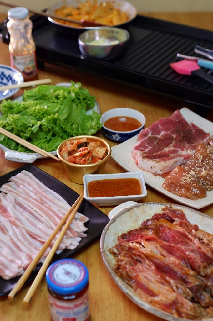 A vibrant Korean BBQ grills at home with a spread featuring fresh meats and sides ready for grilling.