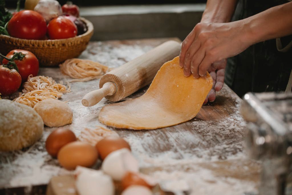 Hands rolling fresh dough for homemade pasta shapes making in a rustic kitchen setting