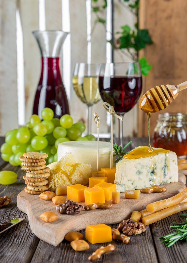 Sophisticated cheese platter with white truffle honey, assorted wines, grapes, honey, and nuts.