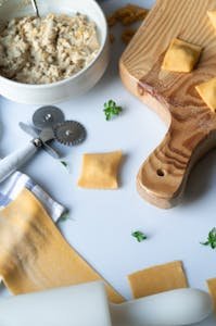 Top view of homemade ravioli preparation with ricotta filling on a wooden board.