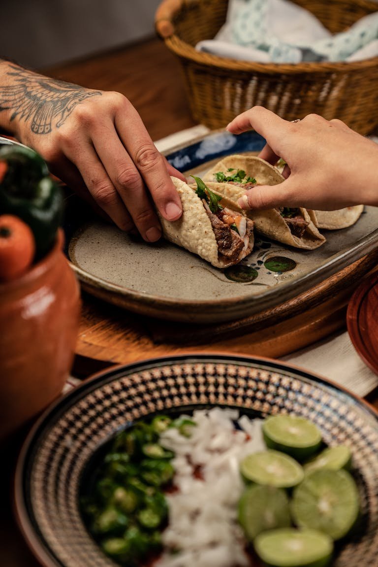Two people enjoying delicious and authentic Mexican dishes with homemade tortillas as tacos served with fresh ingredients on a rustic table.