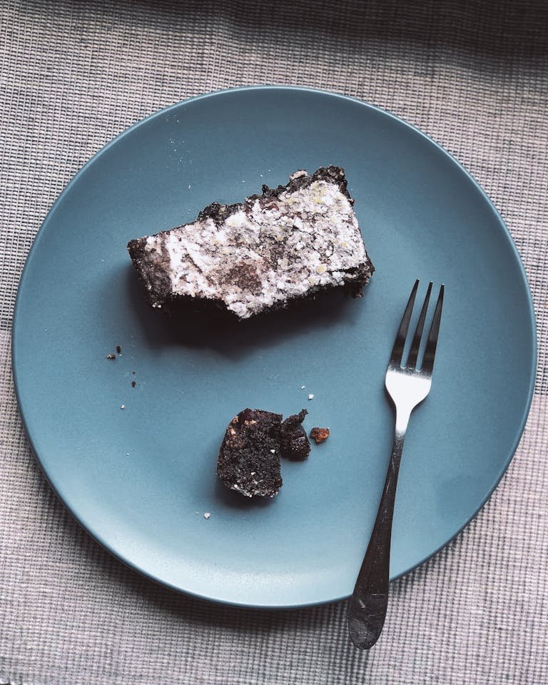 A sugar free dessert of a rustic slice of chocolate cake on a blue plate with a fork, styled for a classic food photo.