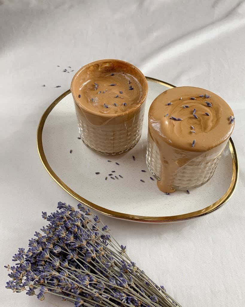 Creamy dalgona coffee topped with lavender on a gentle white background.