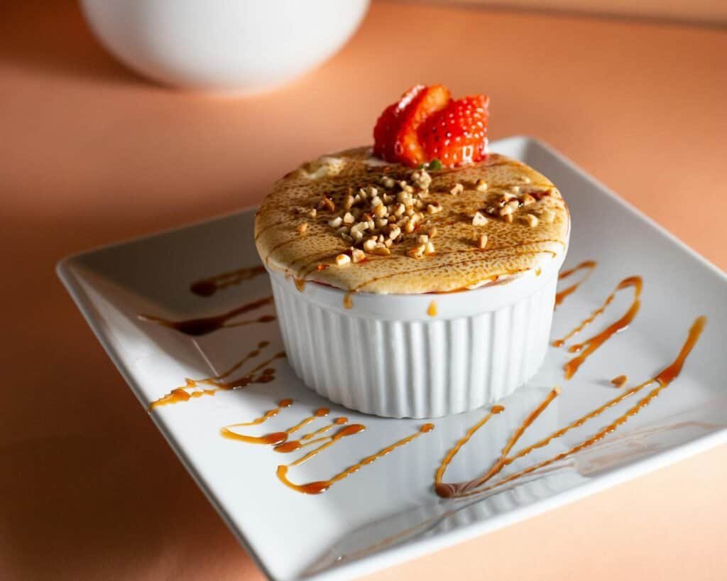 Indulgent crème brûlée garnished with strawberries and nuts, presented elegantly on a plate.