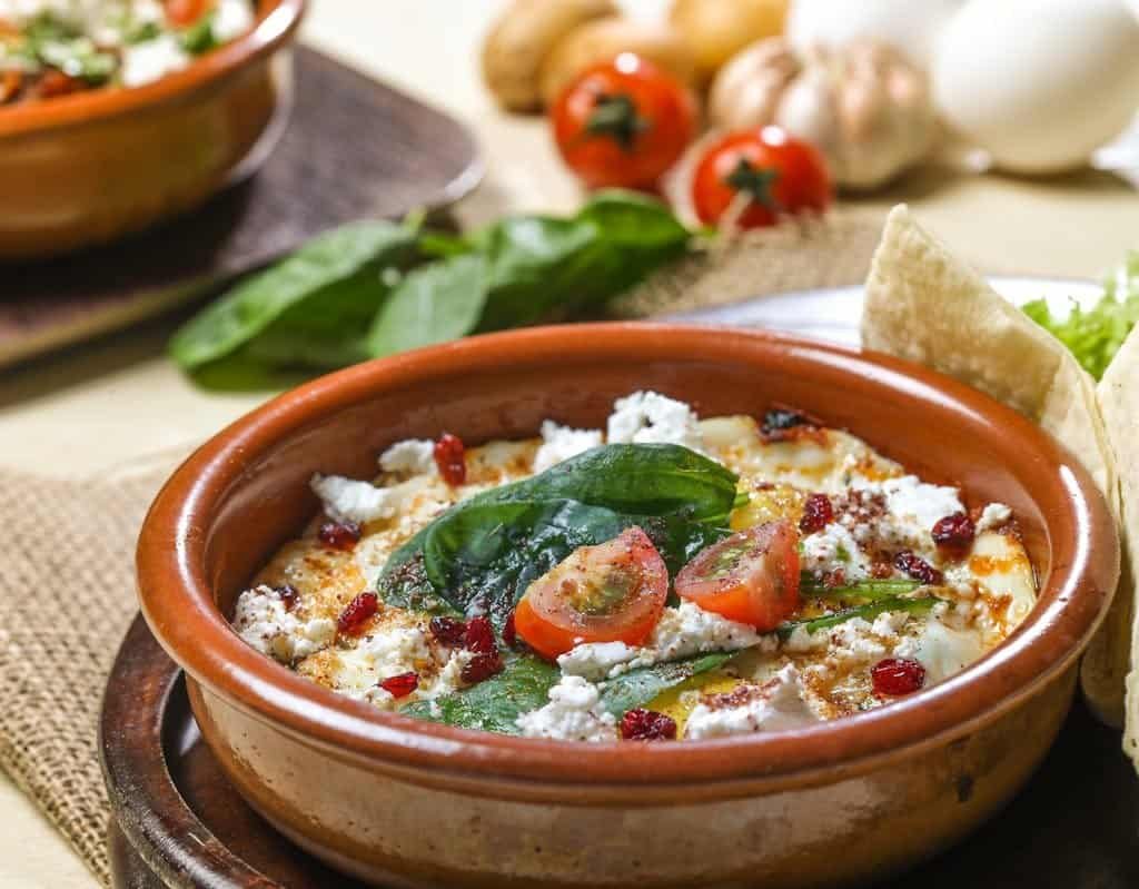 A tantalizing dish of baked feta cheese with spinach and cherry tomatoes, perfect for gourmet lovers.