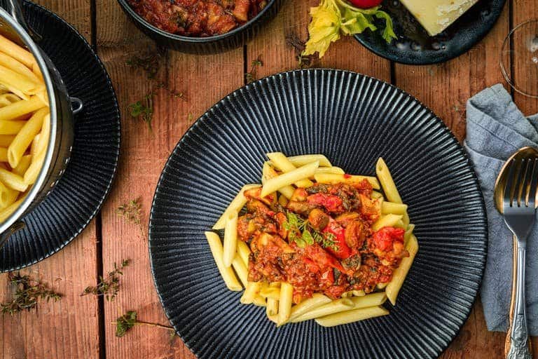 Delicious Italian one-pot-pasta-recipes with hearty tomato sauce served on a dark plate, styled as a flat lay.