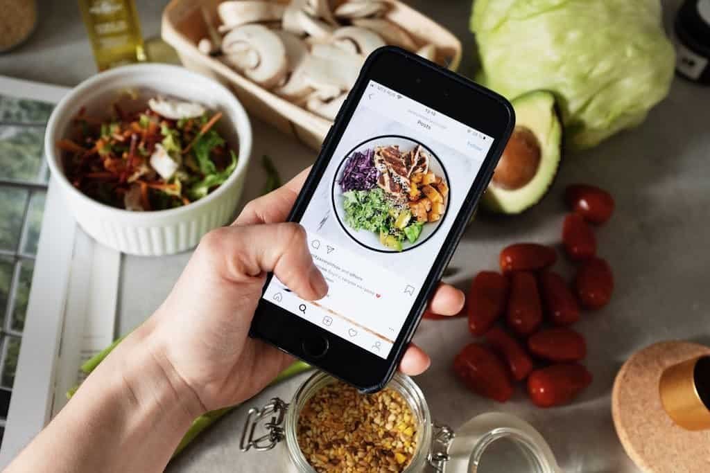 Person takes photo of healthy salad ingredients for social media food trends in the kitchen.
