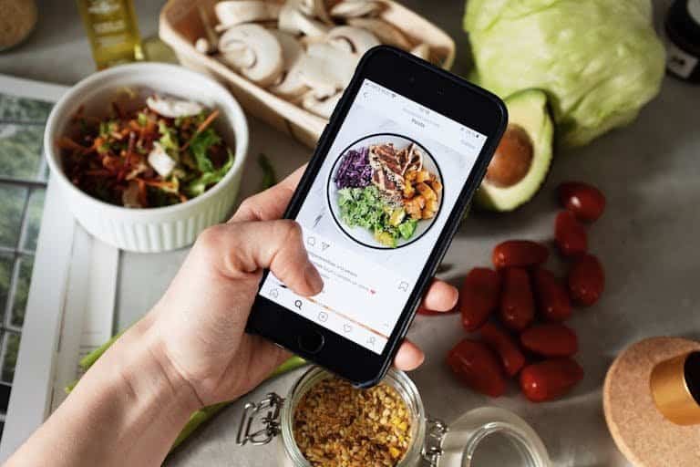 Person takes photo of healthy salad ingredients for social media food trends in the kitchen.