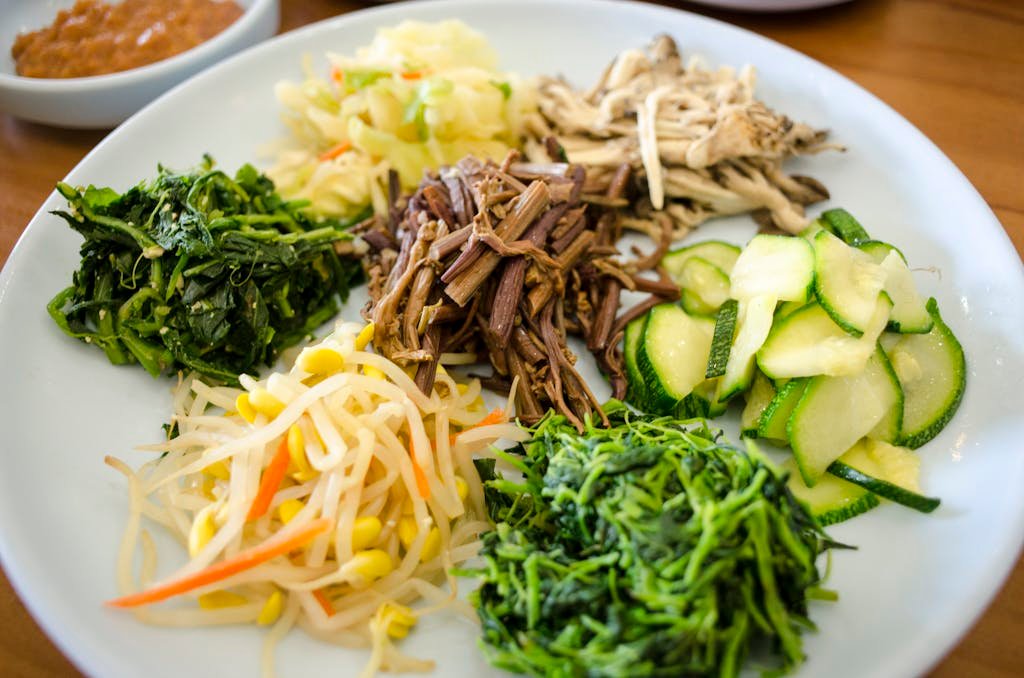 A vibrant assortment of traditional Korean side dishes including vegetables and bean sprouts.