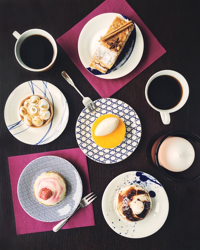 simple no-bake desserts An artistic flat lay of assorted pastries of simple no-bake desserts and coffee cups on a dark table setting, perfect for brunch imagery.