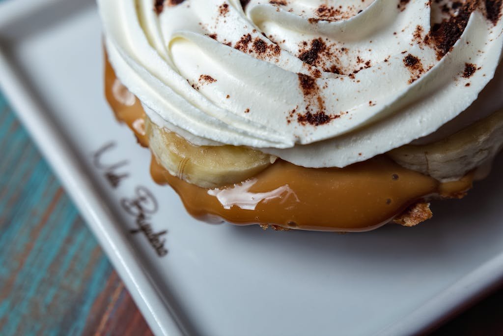 Close-up view of a creamy banoffee pie with caramel, bananas, and whipped cream.