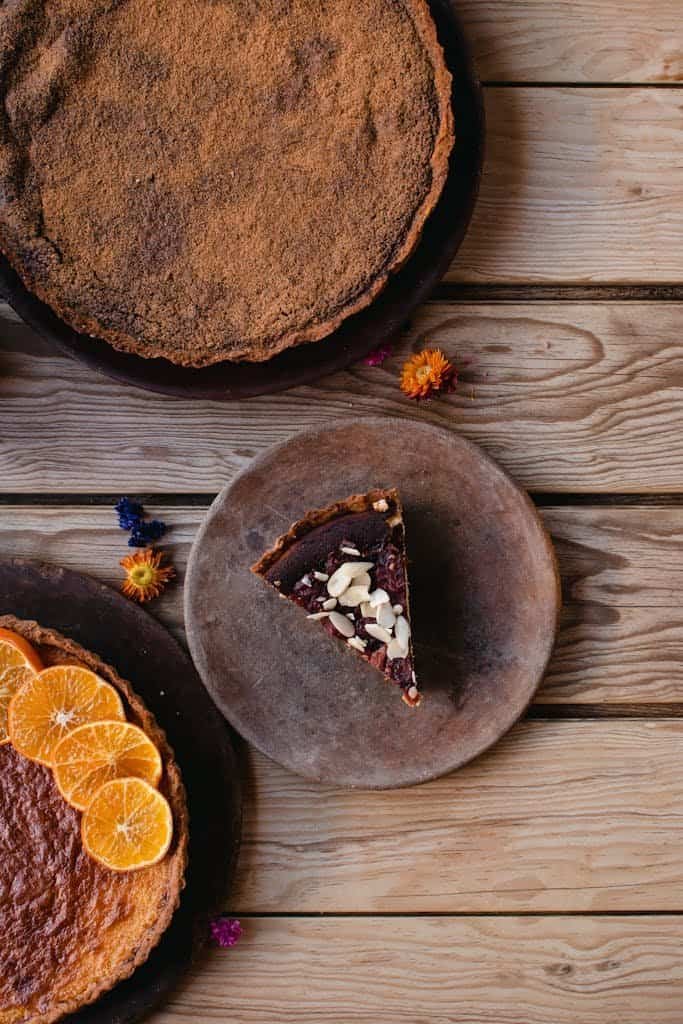 Top view of assorted cakes with toppings on a rustic wooden surface, perfect for food presentations.
