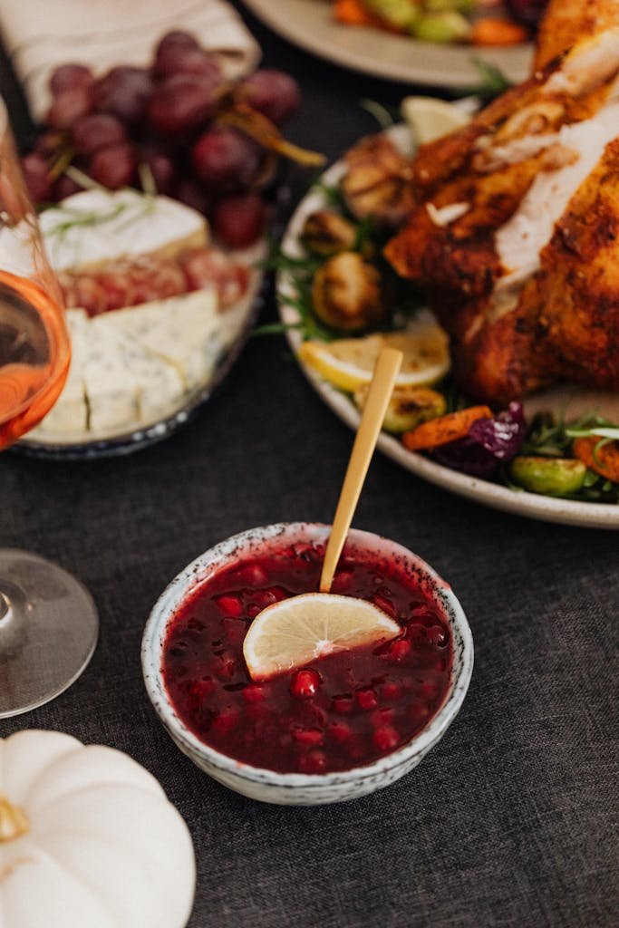 A close-up of a Thanksgiving meal featuring cranberry sauce, roasted turkey, and wine.