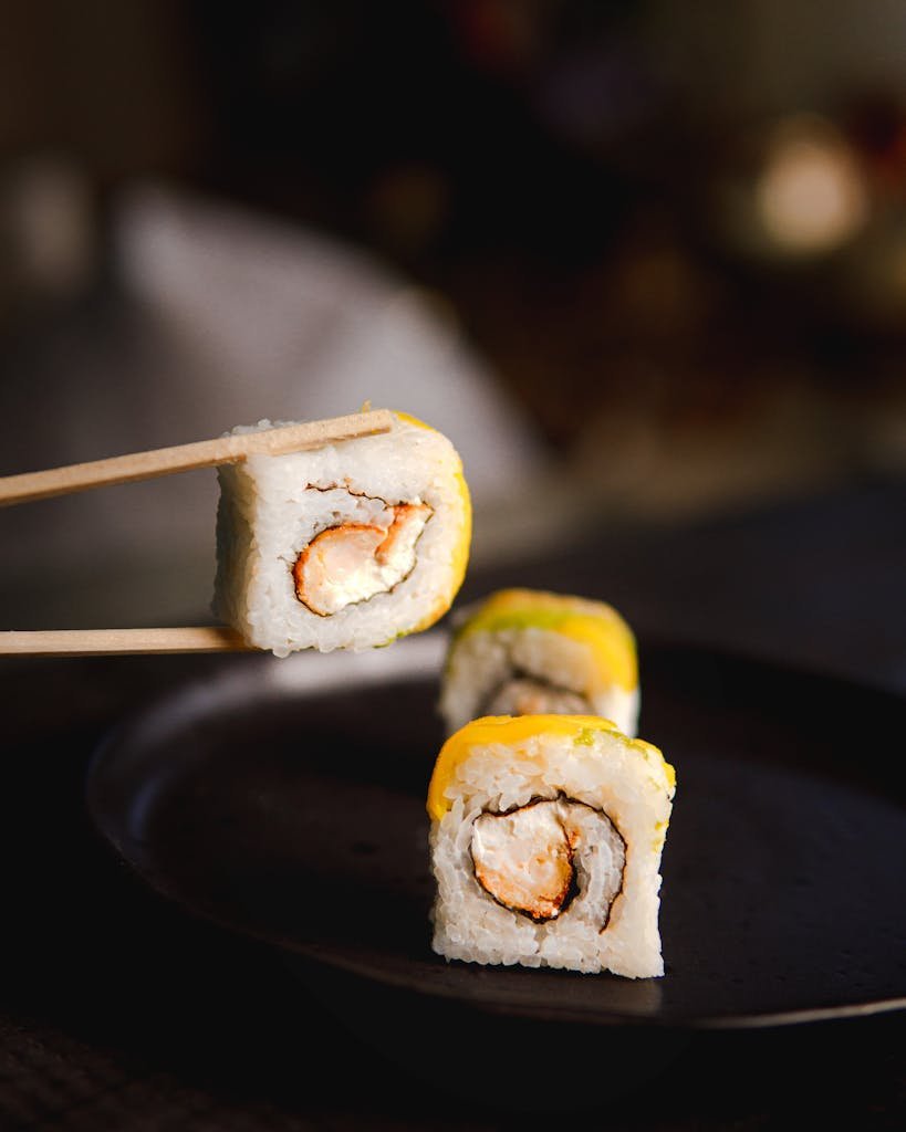 Close-up view of sushi rolls with chopsticks, showcasing Asian cuisine's elegance using a sushi making kit.